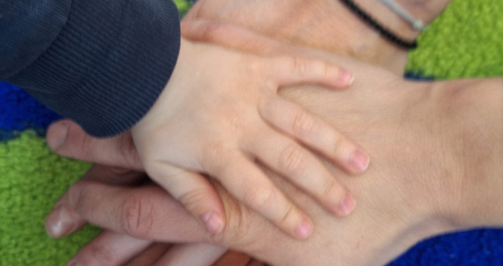 eine Gruppe von übereinander liegenden Händen - ein Kind und zwei Erwachsene