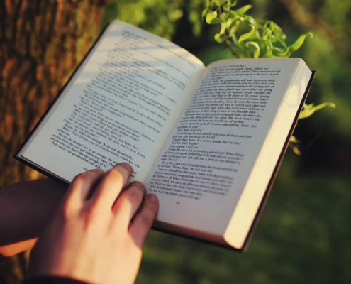 Zeigt ein aufgeschlagenes Buch mit einer Hand am unteren Ende